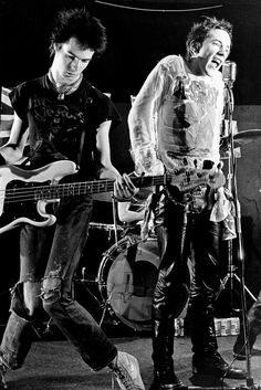 two young men playing guitars and singing into microphones