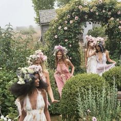 three women in flowered dresses are walking through the garden with flowers on their head