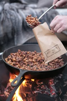 a person is cooking food in a skillet over an open fire with a paper bag