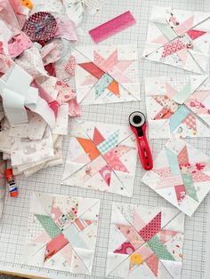 the scissors are laying next to many different pieces of quiltwork on top of a table