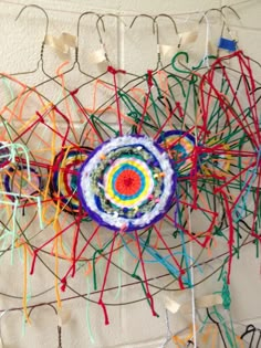 an art piece made out of yarn and crochet on a white wall with wires attached to it