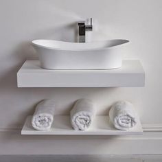 a white bathroom sink sitting on top of a counter next to towels and a faucet