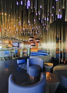 the interior of a modern restaurant with blue chairs and chandeliers hanging from the ceiling