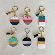 six key chains with different colors and designs on them, one has a tassel