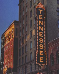 the tenness hotel sign is lit up in front of some tall buildings at dusk