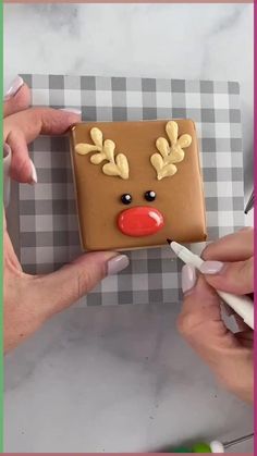 two hands are decorating a cookie with icing and decorations on top of it