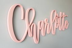 the name charlotte is made out of pink wood and painted with acrylic paint