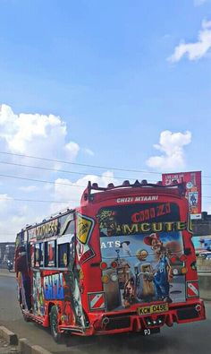 a red bus driving down a street next to a tall building with graffiti on it's side