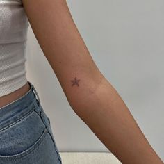 a woman's arm with a small star tattoo on the left side of her arm