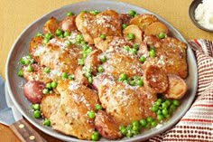 a pan filled with meat and peas on top of a table