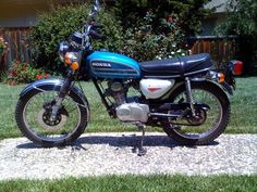 a blue and black motorcycle parked on top of a stone slab in front of a house