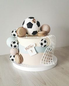 a cake decorated with soccer balls, cookies and macaroons is on a table