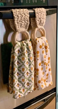 two kitchen towels hanging from the handle of an oven door, one with rings and pineapples on it