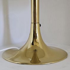 a gold colored table lamp sitting on top of a white surface