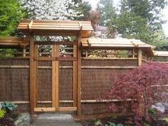 a small wooden structure in the middle of a garden with trees and bushes around it