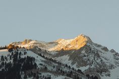 the mountains are covered in snow as the sun is low to the ground on top