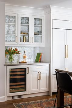 a kitchen with white cabinets and black chairs in front of a wine rack on the wall