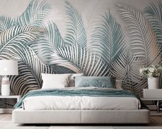 a bedroom with palm leaves painted on the wall and white bed in front of it