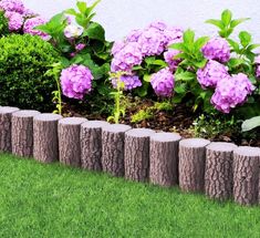 some purple flowers are growing out of the rocks in front of a wall and grass