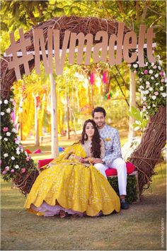 a couple sitting in front of a wreath with the word love spelled out on it