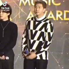 two young men standing next to each other in front of a music award sign and microphone