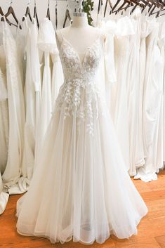 a white wedding dress is on display in front of other dresses