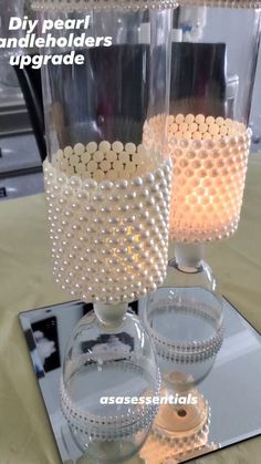 two clear vases sitting on top of a mirrored table with beaded decorations around them