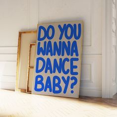 a blue sign that says do you wanna dance baby? in front of a white wall