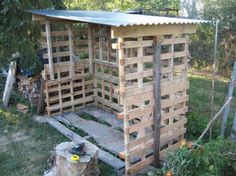 a wooden structure made out of pallets in the grass with trees and bushes behind it