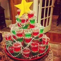 a christmas tree made out of jars filled with jellos and candy sits on a table