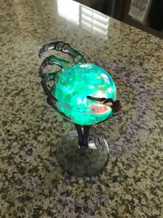 a green glass bowl sitting on top of a counter next to a metal stand with scissors in it