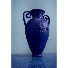 a blue vase sitting on top of a table next to a white wall and floor