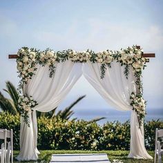 an outdoor wedding ceremony setup with white flowers and greenery on the aisle, overlooking the ocean