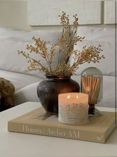 a candle sits on top of a book next to a vase filled with flowers and reeds