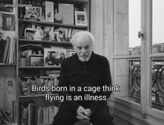 an old man sitting in front of a bookshelf with a quote about birds born in a cage think flying is an illusion