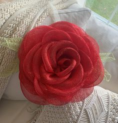 a red flower sitting on top of a white pillow