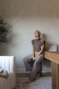 a woman sitting on a chair in front of a table with a potted plant