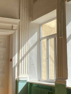 an empty room with green painted walls and white trim on the window sill, along with a radiator