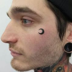 a close up of a person with tattoos on his face and ear piercings in the shape of a crescent