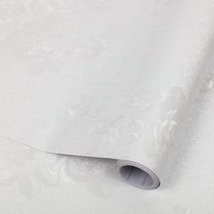 an image of a white wallpaper with floral designs on the paper and it's rolled up