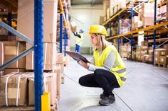 a woman in a yellow safety vest and hard hat is looking at something on the floor