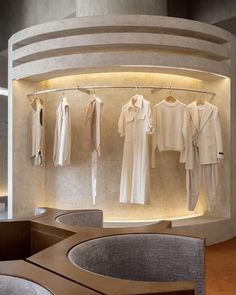 a room filled with lots of white clothes hanging on the wall next to a round table