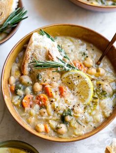 two bowls of soup with lemon slices and bread