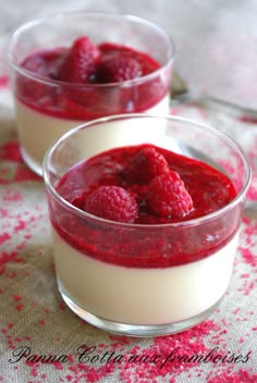 two dessert dishes with raspberries and yogurt in them on a red place mat