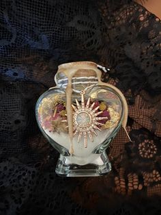 a glass vase filled with assorted items on top of a lace covered table cloth