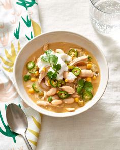 a white bowl filled with beans and vegetables on top of a table next to a glass of water