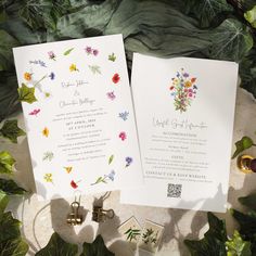 the wedding stationery is surrounded by greenery