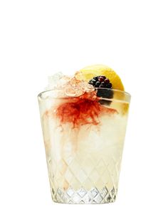 a glass filled with ice and fruit sitting on top of a table