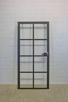 an empty room with a white brick wall and black metal frame doors on each side