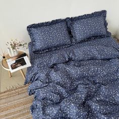 a bed with blue comforter and pillows on top of it next to a table